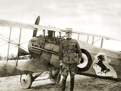 A person in a military uniform stands before a biplane with a lion emblem on its side, suggesting a historical military aviation context.